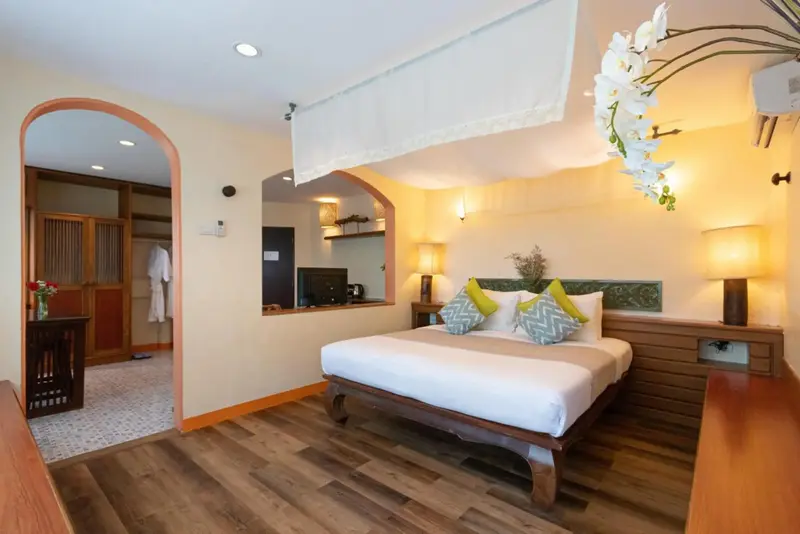 Une chambre lumineuse avec un grand lit à baldaquin et un accès à une salle de bain.