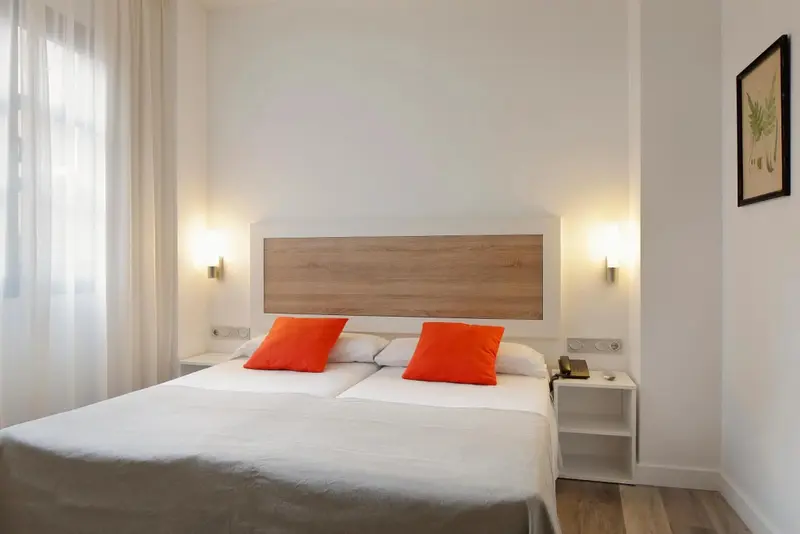 Une chambre lumineuse avec deux lits simples et une décoration sobre.