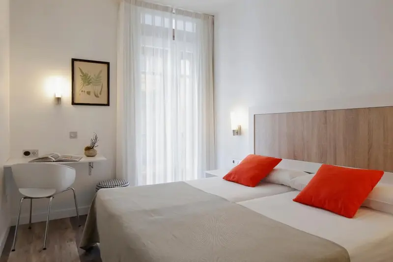 Une chambre lumineuse avec un bureau et un lit double.