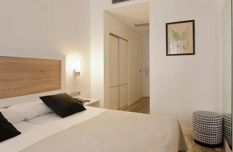 Une chambre lumineuse avec un grand lit et un accès à un autre espace.