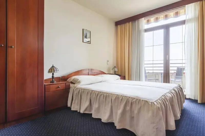 Une chambre lumineuse avec un lit double et un accès à un balcon.