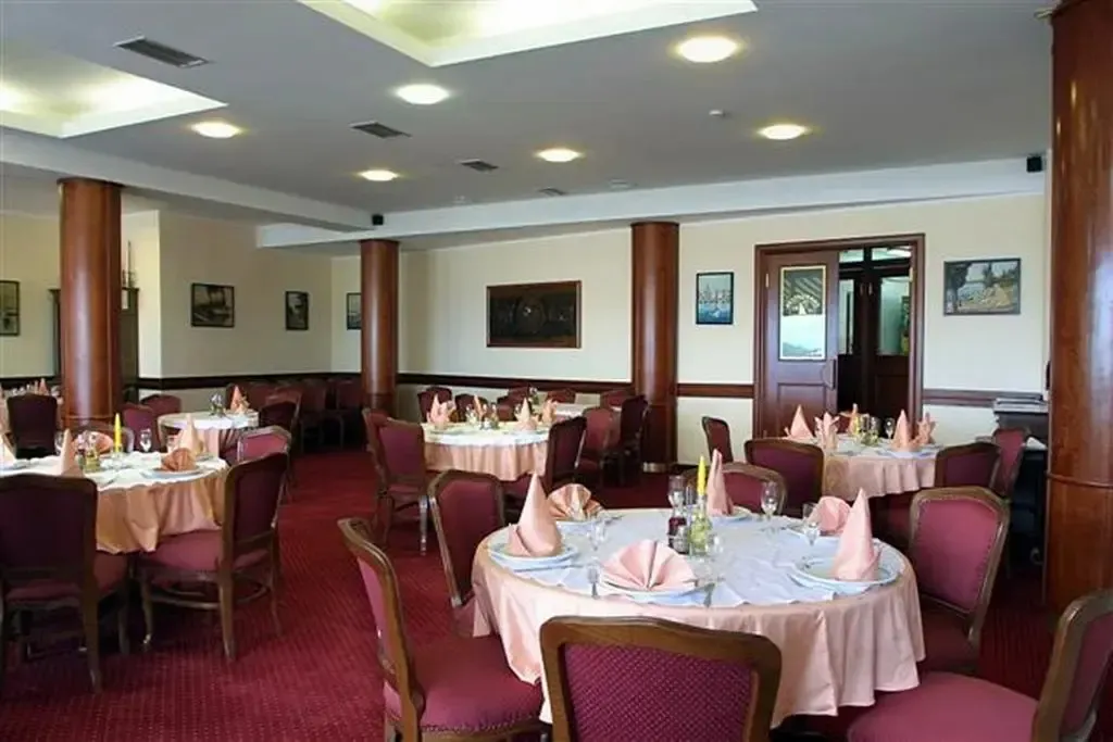 Une salle lumineuse avec des tables rondes nappées et des chaises confortables.
