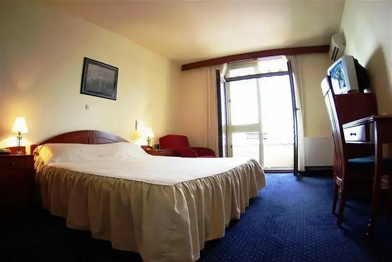 Une chambre lumineuse avec un grand lit et un accès à un balcon.