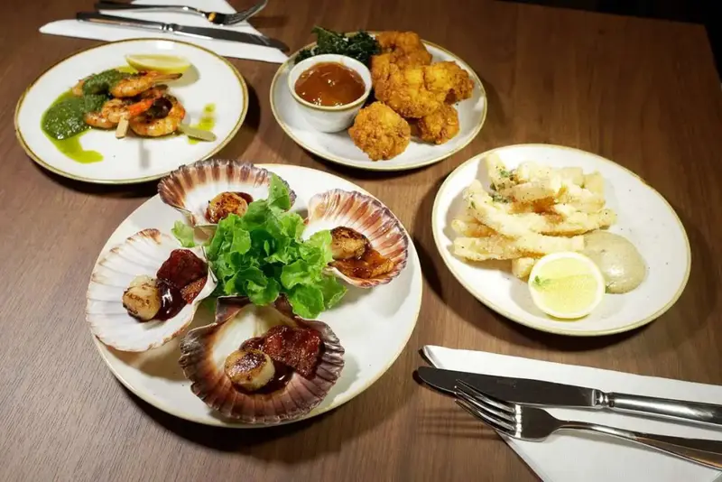 Assiettes de fruits de mer et de plats préparés disposés sur une table en bois.