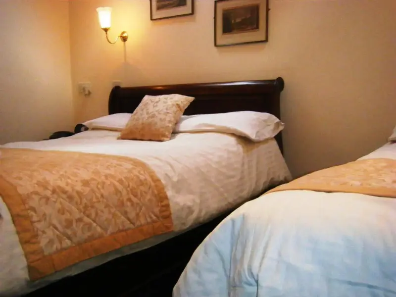 Deux lits simples préparés dans une chambre aux murs clairs.