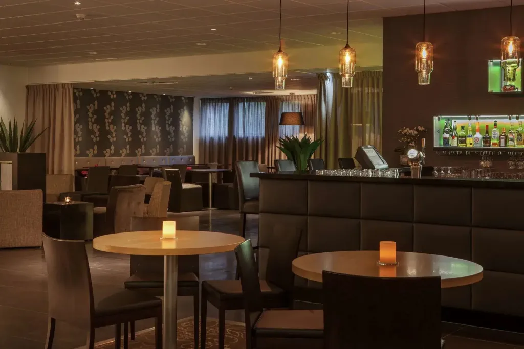 Un espace de détente avec des tables basses et un comptoir de bar en arrière-plan.