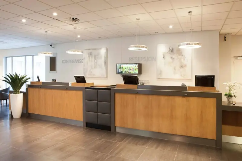 Un comptoir d'accueil moderne en bois clair dans un hall spacieux.