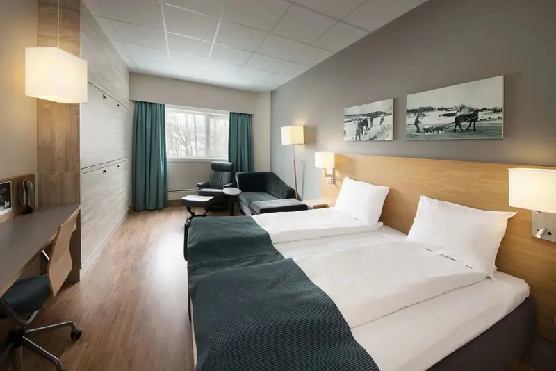 Une chambre lumineuse avec un lit double et un coin salon.