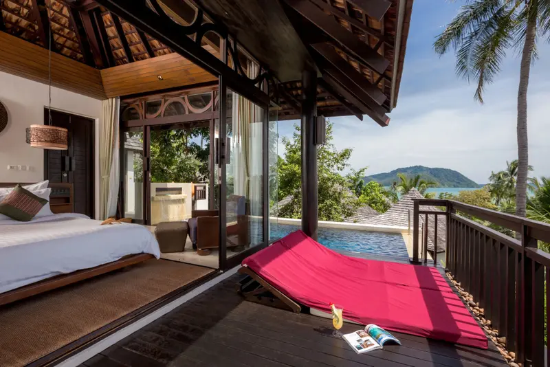 Une chambre s'ouvre sur une terrasse avec transat et piscine.