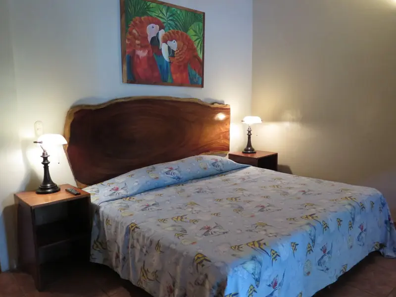 Une chambre lumineuse avec un grand lit recouvert d'une courtepointe colorée.