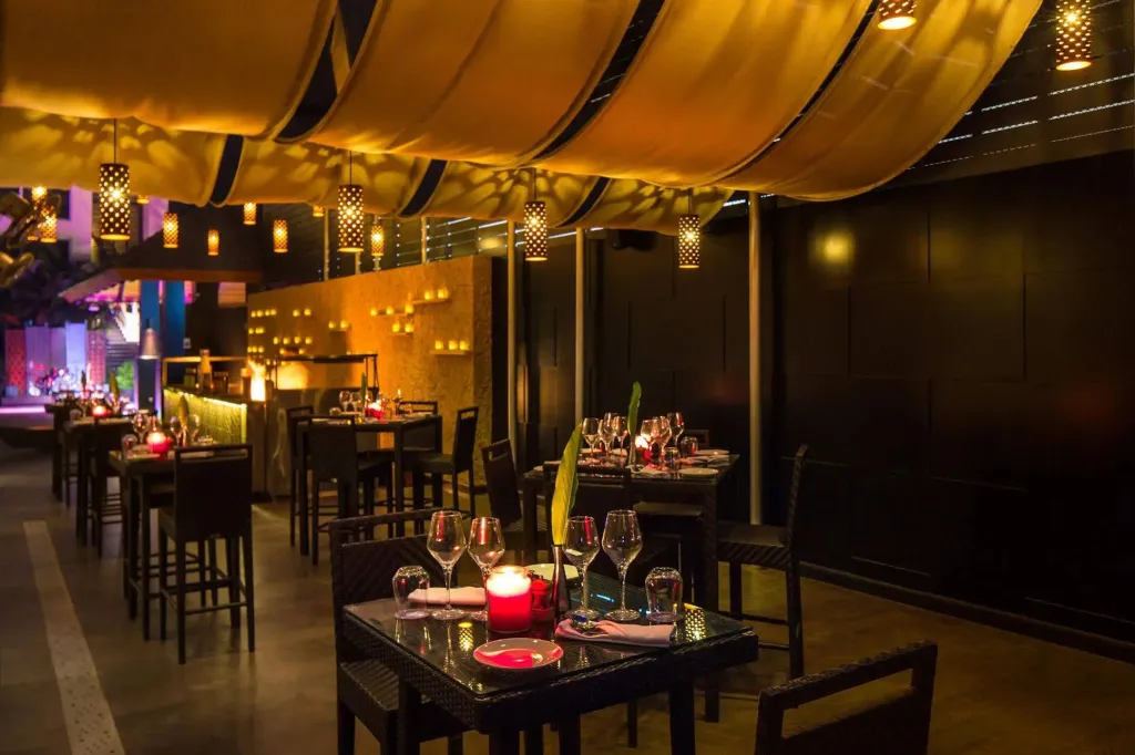 Une salle de restaurant à l'ambiance chaleureuse avec des tables dressées et un bar.