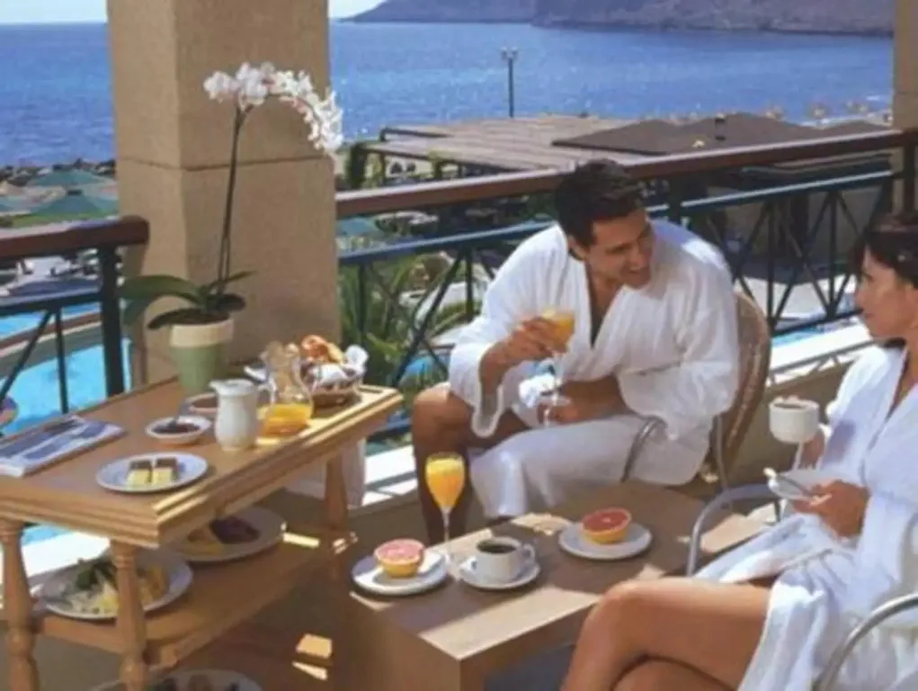 Un couple prend son petit-déjeuner sur une terrasse avec vue sur la mer.