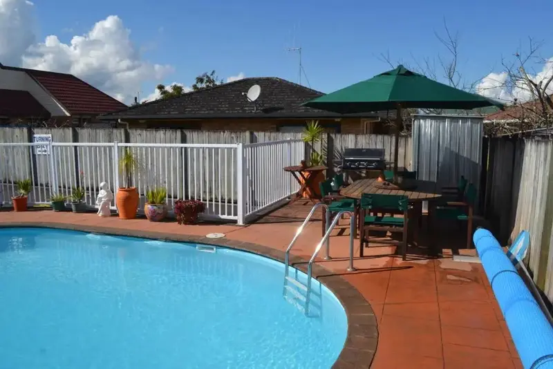 Une piscine rectangulaire avec un espace de détente ombragé à proximité.