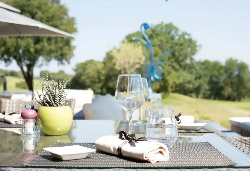 Une table est dressée avec de la vaisselle et des couverts en extérieur.
