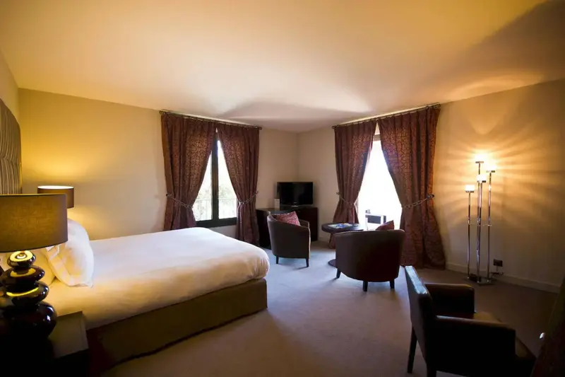 Une chambre lumineuse avec un grand lit et des fauteuils.