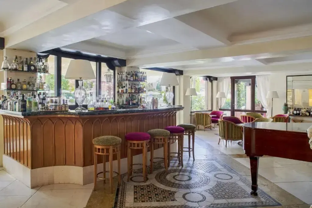 Un bar lumineux avec un comptoir en bois et des tabourets, et un piano à queue dans un espace de détente.
