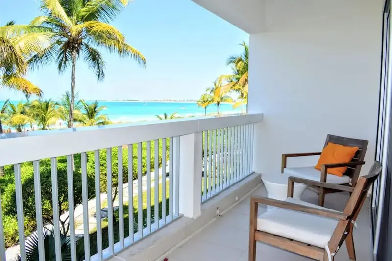 Terrasse avec mobilier d'extérieur donnant sur une plage de sable blanc et la mer.