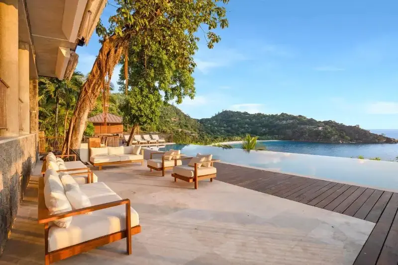 Terrasse aménagée avec salon et piscine à débordement donnant sur une crique.