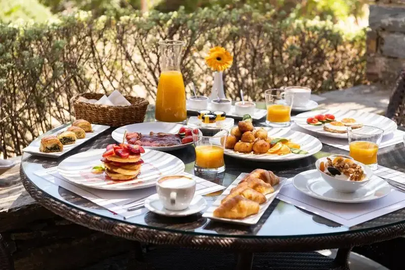 Une table ronde est dressée avec un copieux petit-déjeuner.