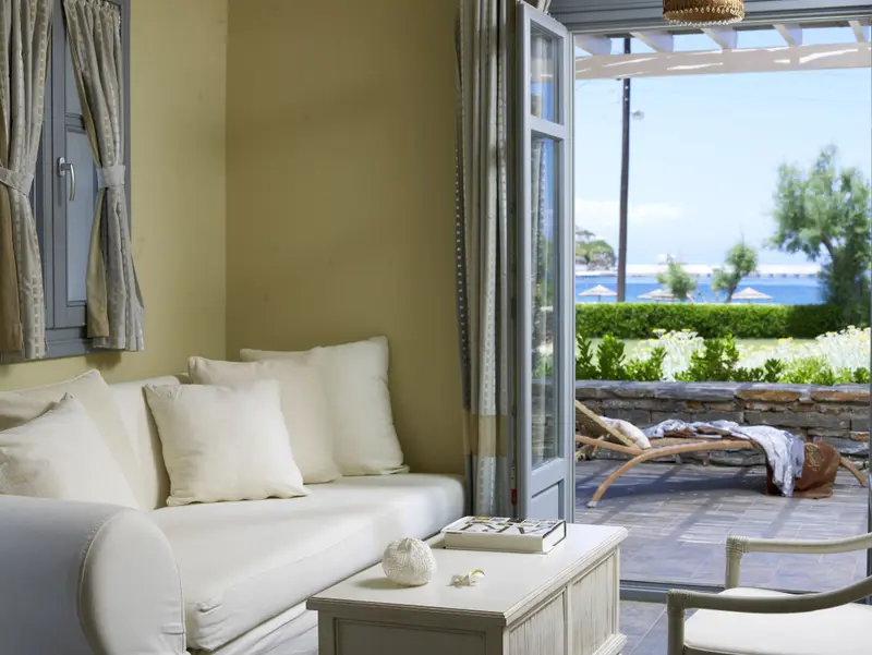 Un espace de détente intérieur s'ouvre sur une terrasse ensoleillée avec vue sur la mer.