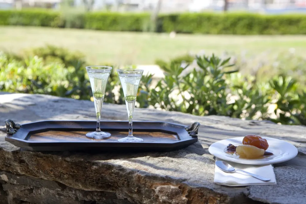 Deux verres de boisson fraîche accompagnés d'une assiette de fruits sur une table en pierre.
