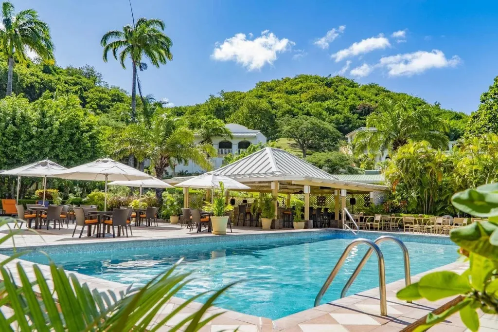Une piscine bordée de chaises longues et de parasols, avec un bar en arrière-plan.