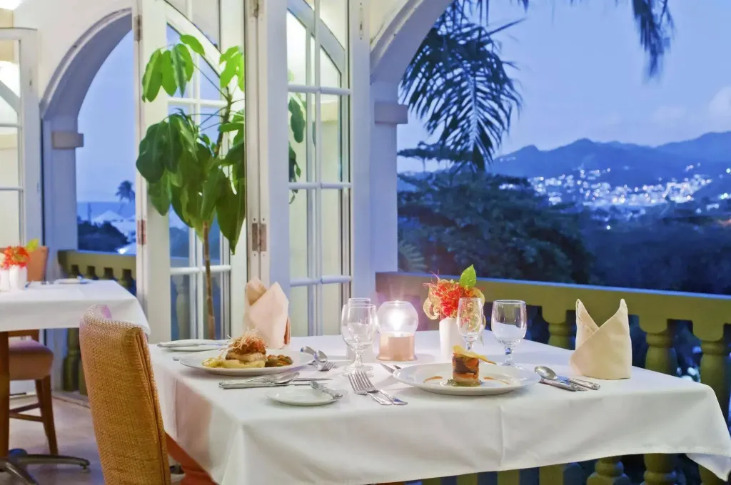 Une table dressée en extérieur offre une vue sur un paysage urbain illuminé au crépuscule.
