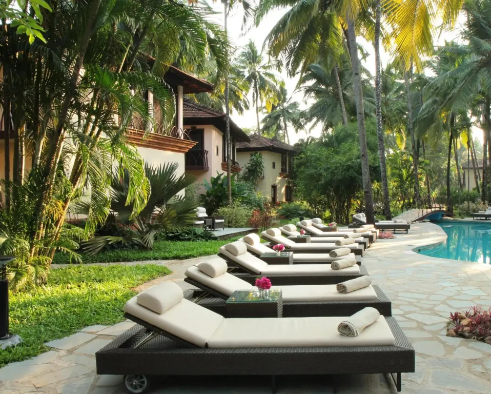 Transats alignés au bord d'une piscine dans un jardin tropical.
