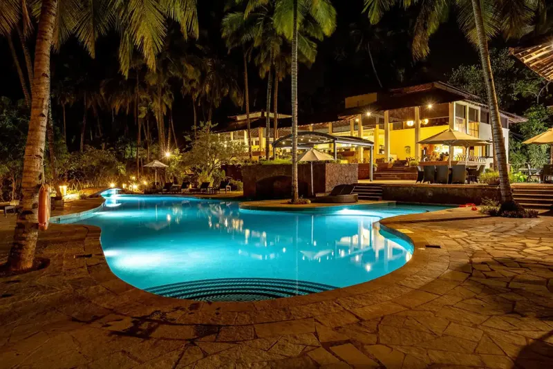 Piscine illuminée au premier plan avec bâtiment éclairé en arrière-plan.