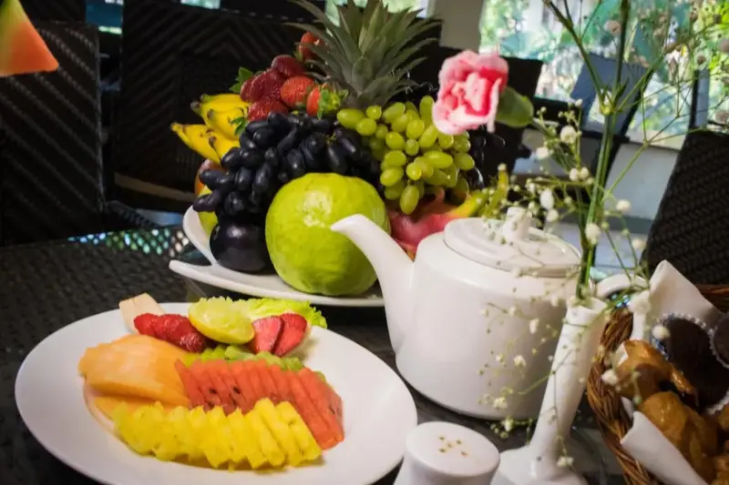 Une table est garnie d'une abondance de fruits frais et d'une théière.