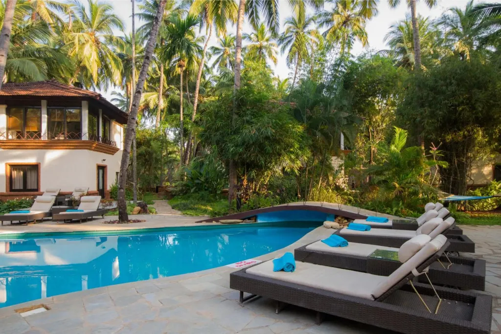Transats confortables au bord d'une piscine turquoise dans un cadre tropical.