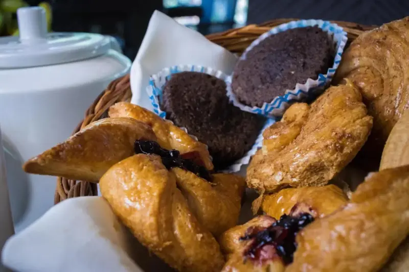 Assortiment de viennoiseries et de muffins dans un panier en osier.