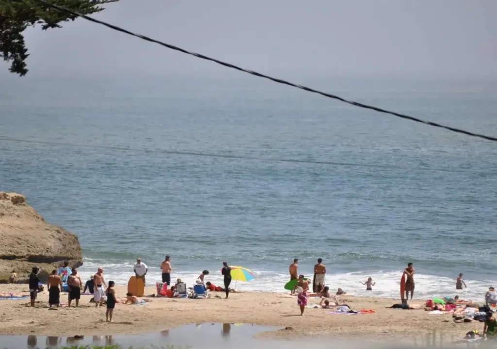 Une plage ensoleillée avec des personnes se relaxant et se baignant.