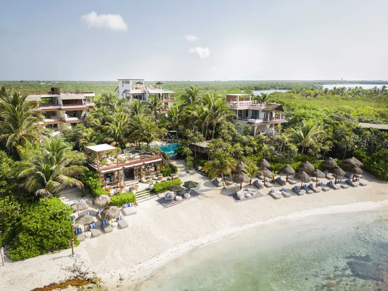 Vue aérienne d'un complexe hôtelier bordant une plage de sable blanc.