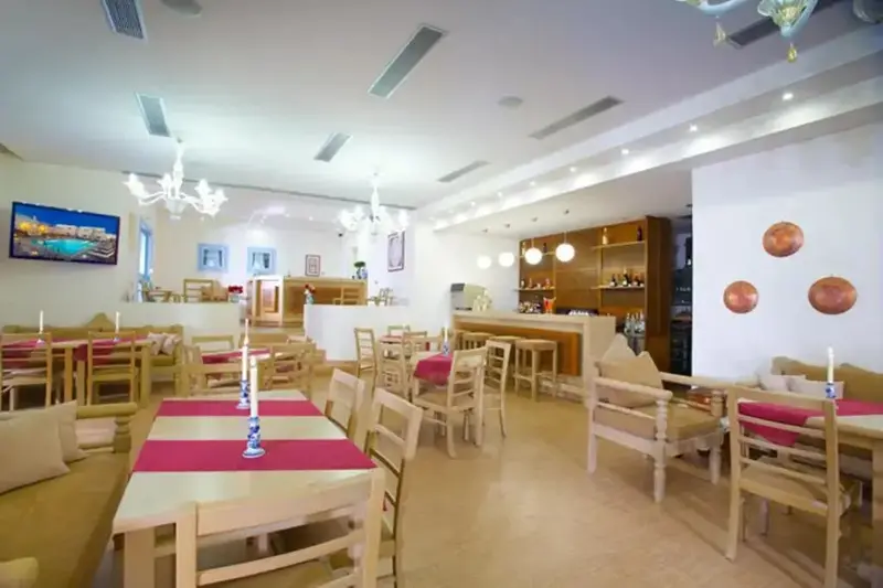 Une salle lumineuse avec des tables et des chaises, un bar et des luminaires décoratifs.