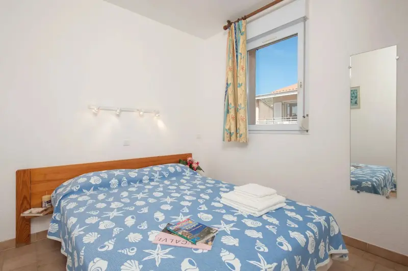 Une chambre lumineuse avec un lit recouvert d'une couette à motifs et un miroir.