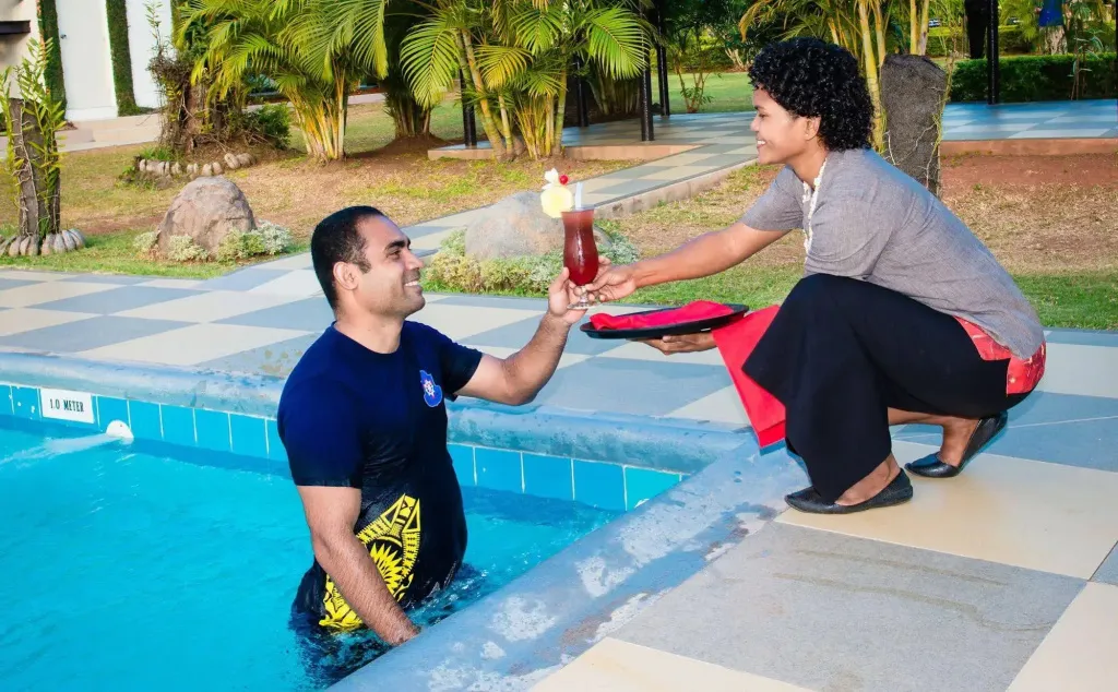 Une personne sortant d'une piscine reçoit des boissons d'une employée.