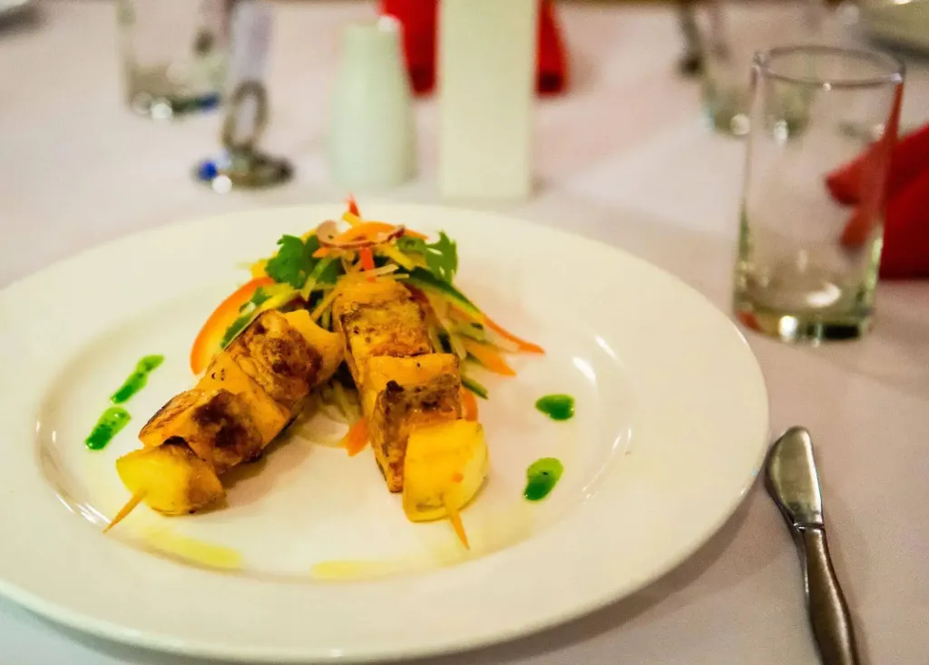 Assiette de brochettes de poisson et de légumes frais décorée de sauce.