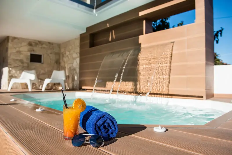 Une piscine avec une cascade et des chaises longues.