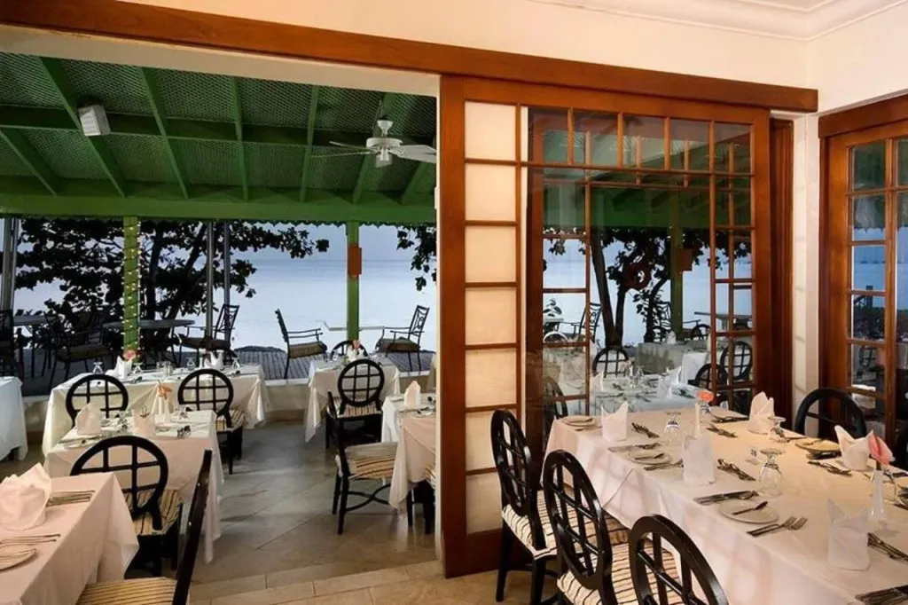 Une salle à manger lumineuse avec des tables dressées face à la mer.