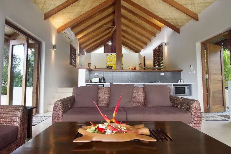 Espace de détente intérieur avec canapé et table basse décorée de fleurs tropicales.