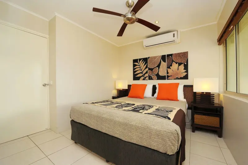 Une chambre lumineuse avec un grand lit et des coussins orange.