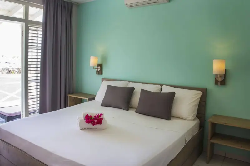 Une chambre lumineuse avec un lit double et des oreillers décoratifs.