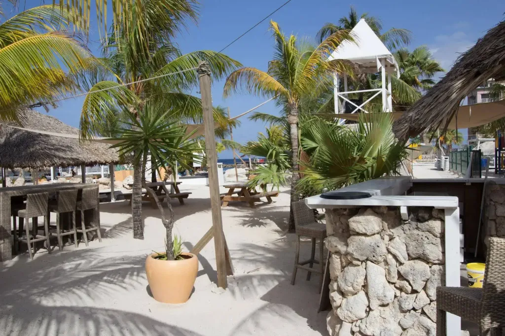 Un bar de plage ombragé par des parasols offre des places assises sur le sable.