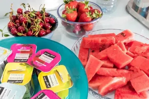 Assortiment de fruits frais et de compotes individuelles présentés sur une table.