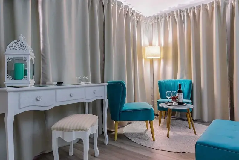 Un coin salon avec une table et des fauteuils turquoise.