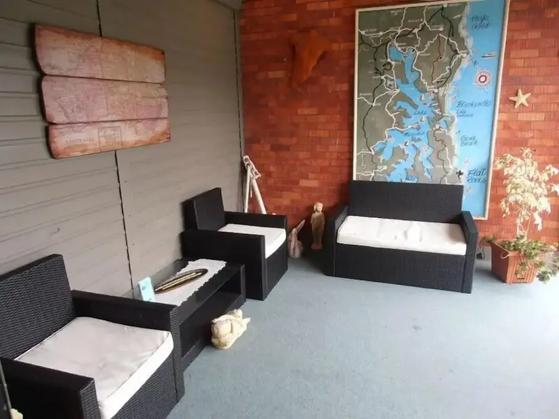 Espace de détente extérieur avec mobilier en résine tressée et carte marine décorative.