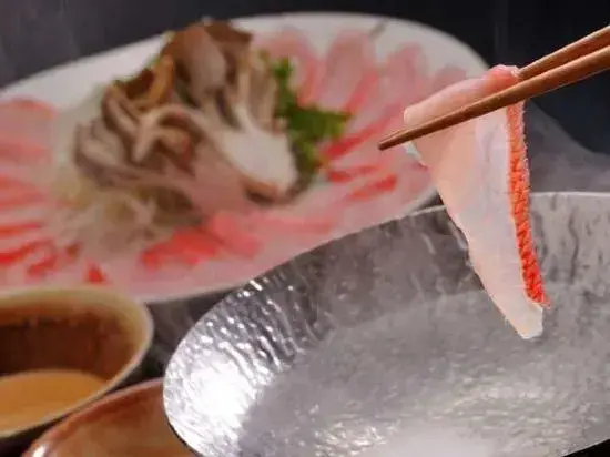 Assiette de sashimi de poisson cru présenté avec des baguettes et des accompagnements.
