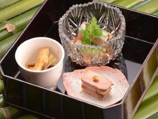 Présentation raffinée de plusieurs mets dans un plat noir laqué.