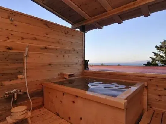 Baignoire en bois sur une terrasse en bois avec vue sur la mer.